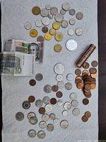 Overview of entire lot with mixed coins, roll of pennies, two banknotes