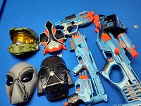 Overview of all Nerf blasters and masks on blue surface