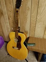 Full view of guitar on stand with harmonica case nearby