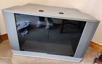 Front view of grey laminate corner TV stand with closed smoked glass doors