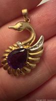 Front view of swan pendant showing amethyst, diamonds and 14k yellow gold body