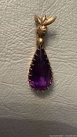 Front view of gold pendant with amethyst stone