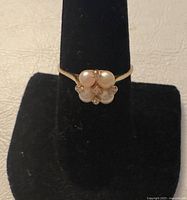 Front view of ring on display stand showing pearl and diamond cluster