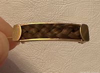 Side view of gold bar pin showing braided hair panel and endcaps