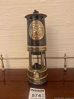 Full view of brass and steel miners lamp on table