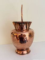 Full view of hammered copper pitcher, handle upright