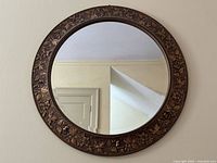 Front view of round mirror showing full copper-tone floral frame and reflective surface