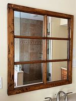 Front view of six-pane wooden framed mirror hanging on wall