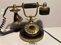 Full view of gold plated rotary telephone showing handset, cradle, dial and cord