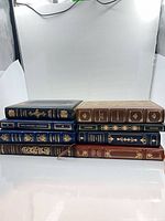 Eight books stacked to show gilt page edges and covers