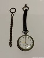 Pocket watch, leather strap and chain laid out