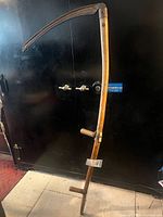 Full view of scythe showing wooden snath, hand grips, and blade
