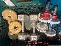 Basket containing beige York plates, 25 lb hex dumbbells, spin-lock bars with red collars and grey plates