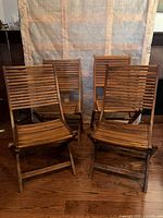 Front angle view of four teak folding chairs