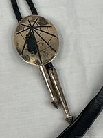 Front view of sterling bolo tie showing medallion design and tips