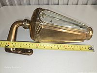 Side view of brass limousine side lamp with mounting bracket and measuring tape showing roughly 27 cm length