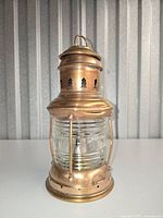 Front view of polished brass marine kerosene lantern showing glass globe and support arms