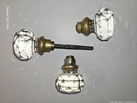 Two crystal glass doorknobs attached to spindle and third knob separate