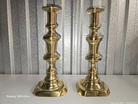 Front view of both brass candlesticks standing side by side