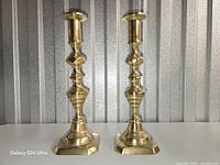 Front view showing pair of polished brass candlesticks on square bases