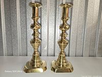 Pair of polished brass push-up candlesticks front view