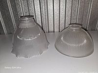 Both ribbed glass lamp shades side by side showing differing rim styles