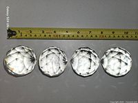 Four faceted crystal spheres aligned under tape showing approx 2.5 in diameter