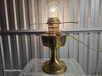 Front view of brass Aladdin 23 lamp lit with bulb