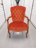 Front view of orange velvet tufted armchair