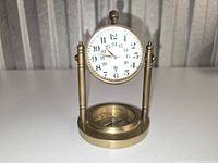 Front view showing clock face, compass, brass pillars and base