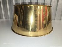 Side view of brass lamp shade showing reflective finish and taper
