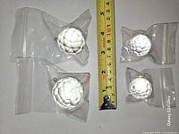 Four faceted crystal balls in zip bags beside tape measure showing scale