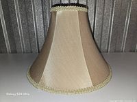 Side view of gold silk bell lamp shade showing fabric and braid trim