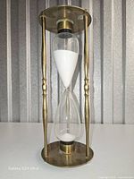 Full view of brass hourglass showing frame, glass bulbs and white sand