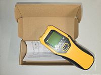 Stud finder resting on open cardboard box with manual visible