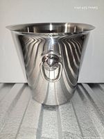 Front view of brushed stainless steel ice bucket showing ring handle and tapered shape