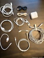 Group of cables, adapters, EarPods and Apple power adapter on table