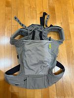 Front view of two-tone grey Boba Classic baby carrier laid flat showing main body and waist belt