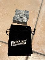 Nine soapstone cubes arranged on tile beside branded pouch