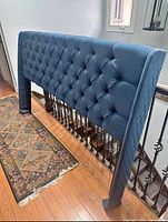 Front view of midnight blue diamond-tufted king headboard with wing sides