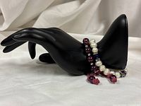 Two bracelets displayed on black hand form