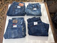 Four folded pairs of blue jeans with size notes visible