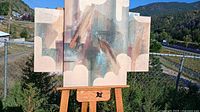 Full view of three-panel abstract painting on easel outdoors