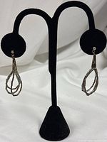 Full view of both sterling liquid silver dangle earrings on display stand