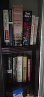 Upper corner shelf showing Shakespeare volume, Tom Clancy novel and other hardcovers