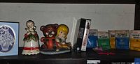 Shelf with angel bell, teddy bear and girl figurine, greeting card, PC games spine, cue card guides