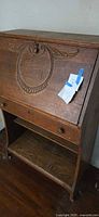 Front view of oak secretary desk with carved drop front closed