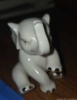 Front angle of white porcelain elephant, showing gold accents on feet and eyes