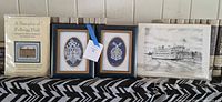 Group shot of sealed sampler kit, two framed lace pieces, unframed riverboat print