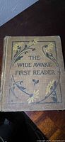 Front cover of The Wide Awake First Reader showing title and decoration